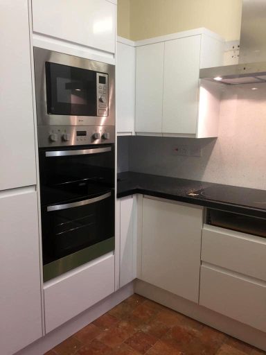 Modern kitchen with built-in oven and microwave, sleek cabinets, and dark countertops.
